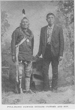 Pawnee father and son, Oklahoma, ca. 1912 Black and white archive photo from 1912 showing a Native American man in traditional dress next to his son wearing European clothing